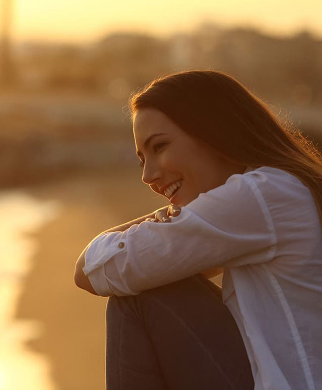 woman sitting outside during sunset, happy